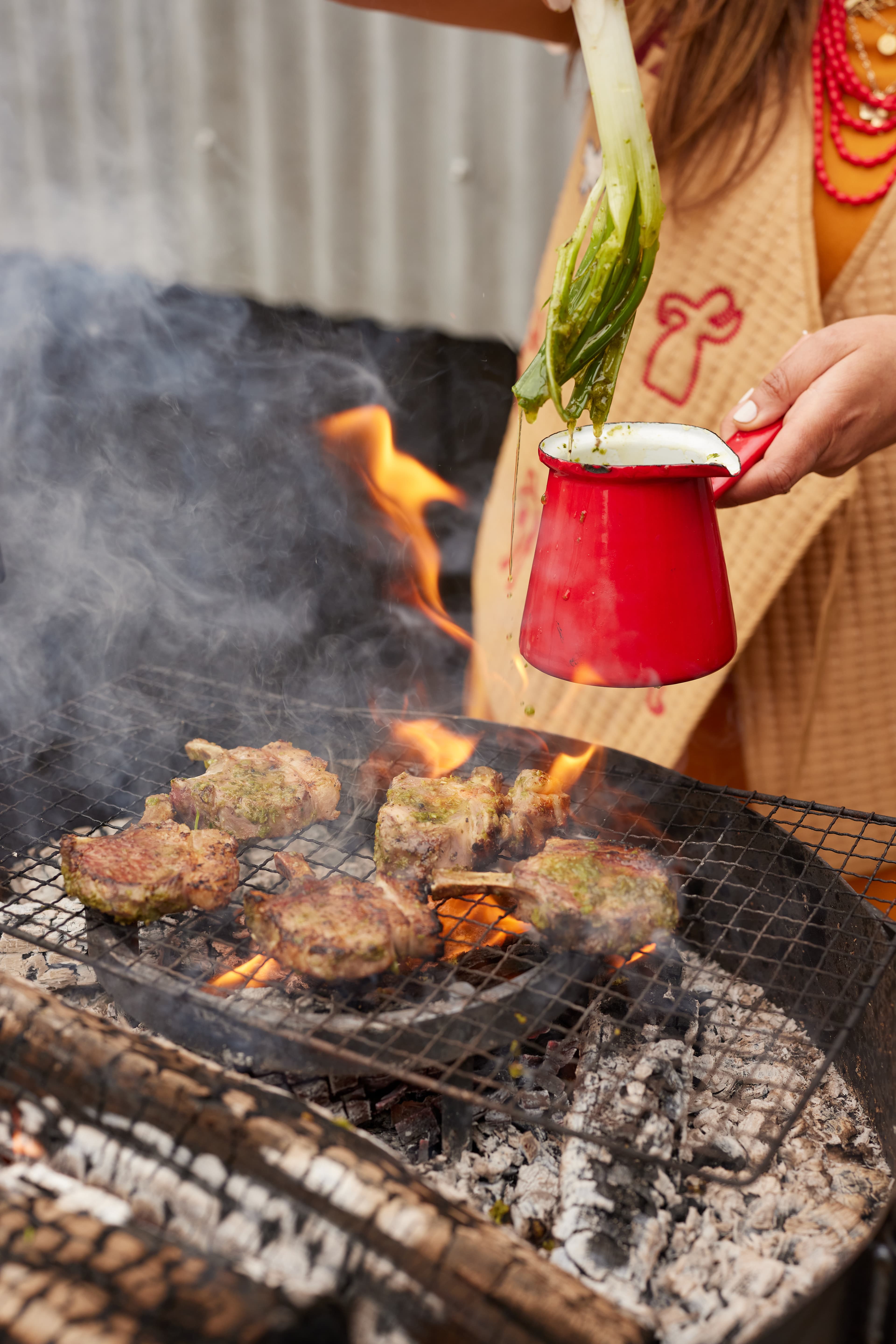 Basting lamb cutlets over fire