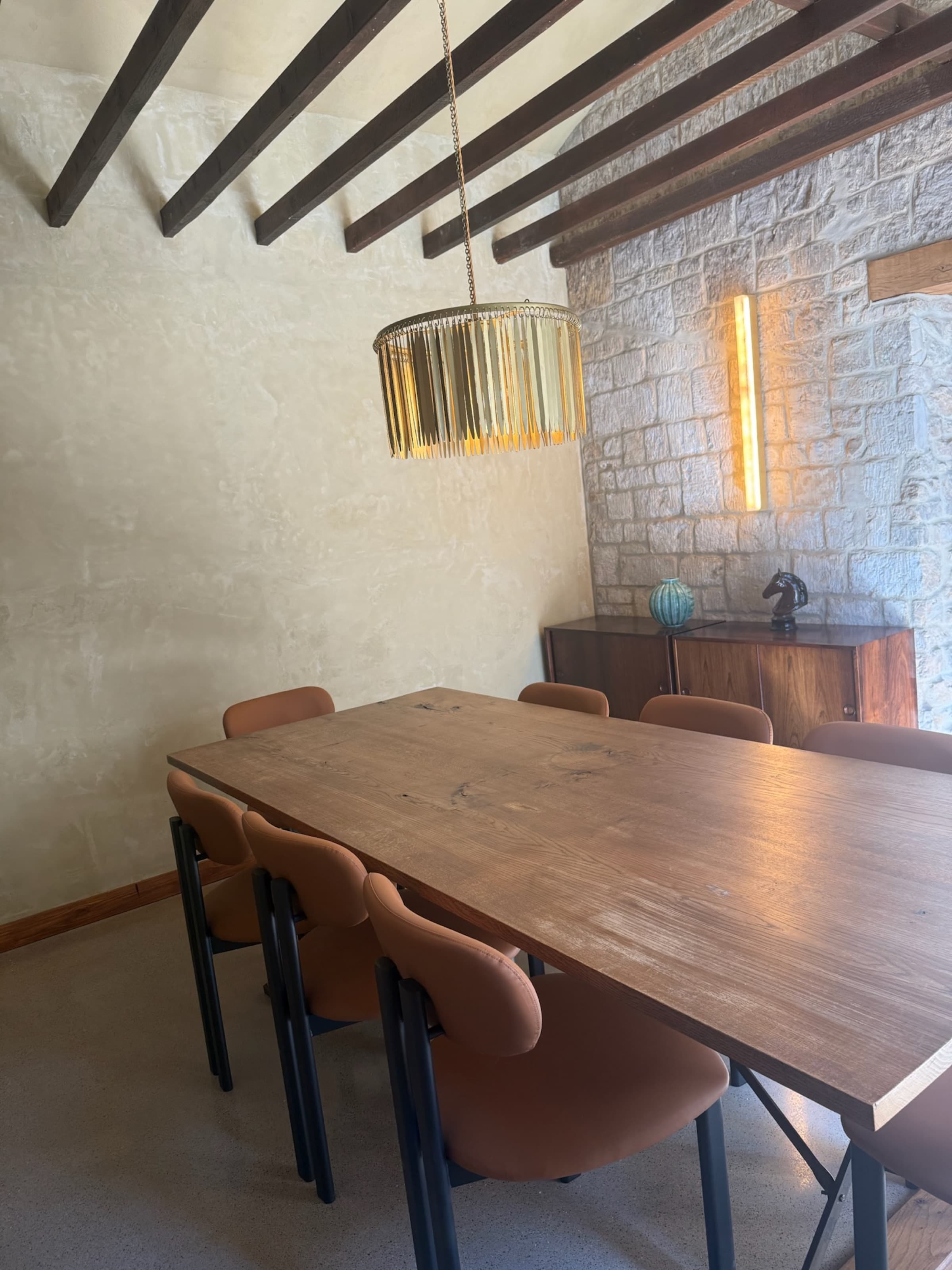 Dining room, exposed stone wall and brass linear light