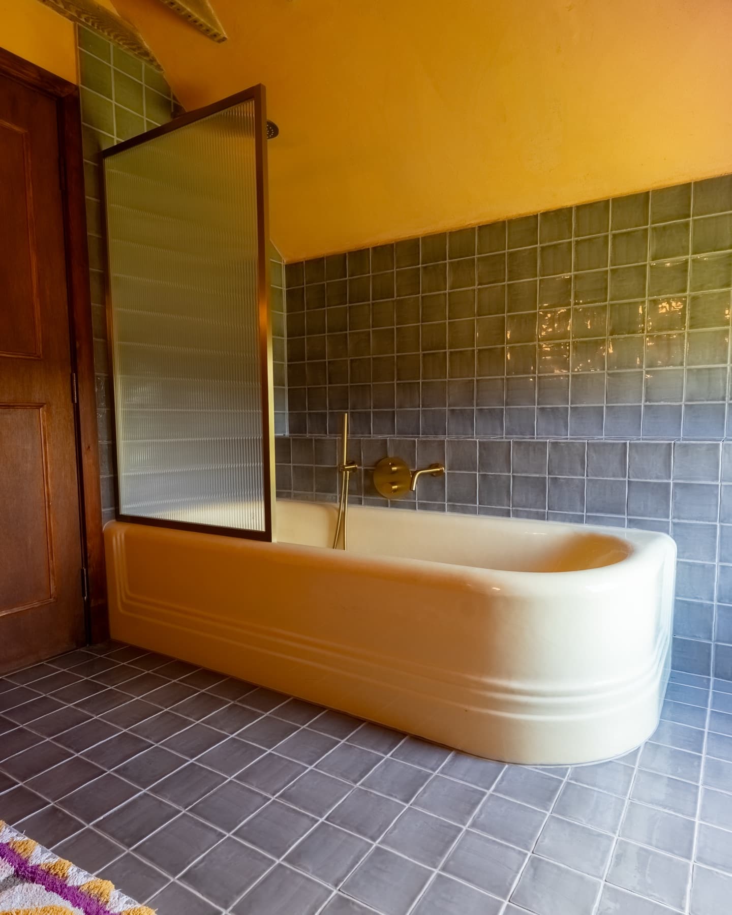 Ensuite bathroom with yellow bathtub and blue-grey tilework