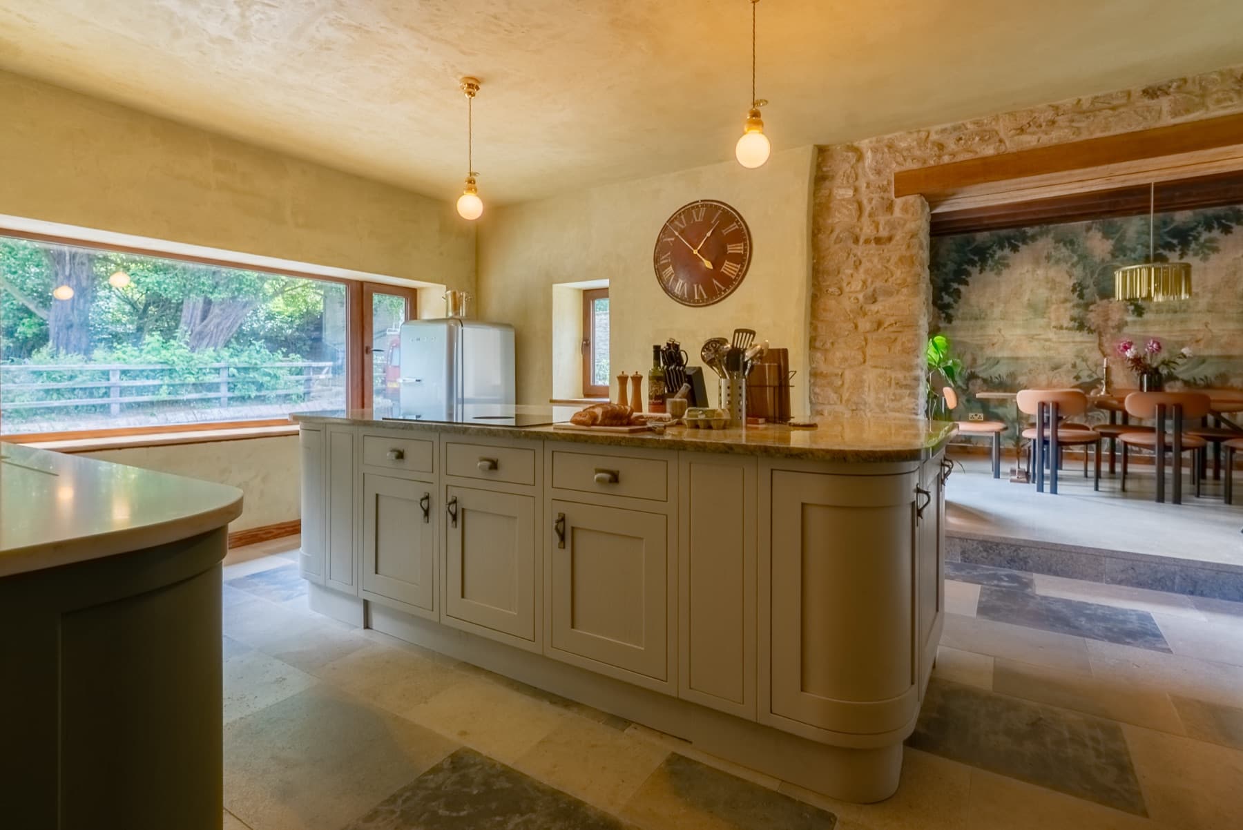 Kitchen island with marble worktop, sage cabinetry and exposed stone