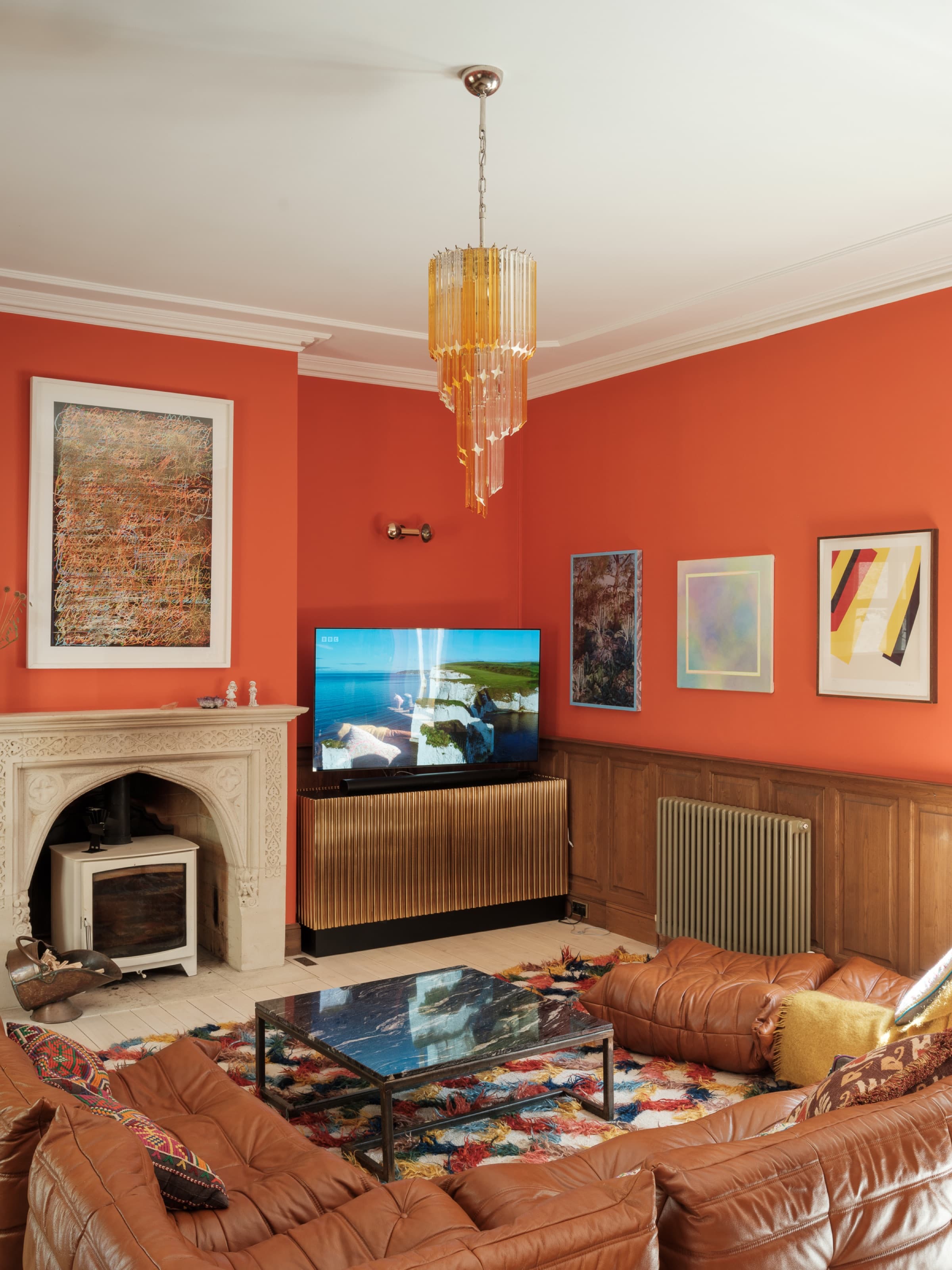 Somerleaze sitting room with coral walls, Murano chandelier, leather sofas